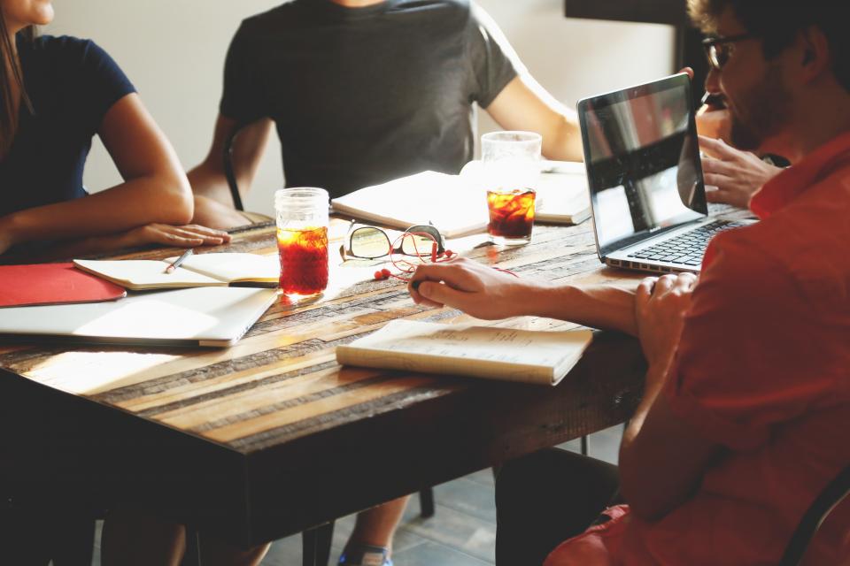 A team of analysts working together with laptops and notes around a table
